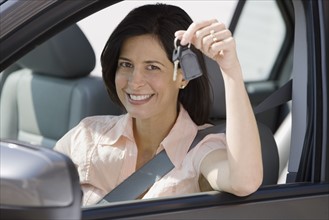 Woman holding car keys in car.