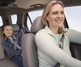 Mother driving car with daughter in back.