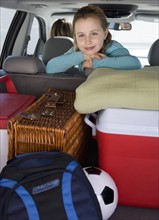 Girl in car with picnic supplies.