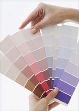 Close up of woman comparing paint swatches.