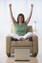 Indian woman cheering in armchair.