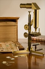 Old fashioned microscope and slides on table.
