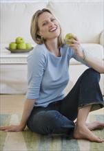 Woman holding apple on floor.