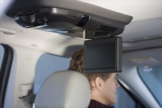 Television screen in car with man driving.