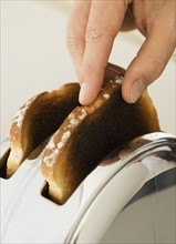 Man taking toast out of toaster.