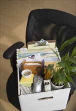 Box of office items on chair.