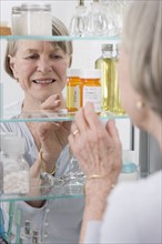 Senior woman looking in medicine cabinet.