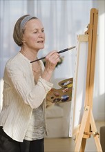 Senior woman painting on easel.