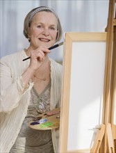 Senior woman painting on easel.