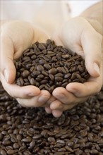 Person holding handful of coffee beans.