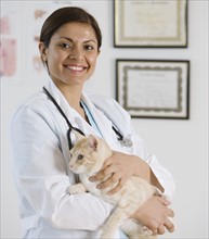 Indian female veterinarian holding cat.