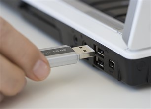 Man plugging USB stick into laptop.