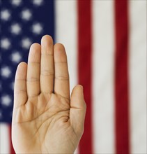 Man’s hand up in front of American flag.
