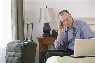 Businessman with suitcase in hotel room.