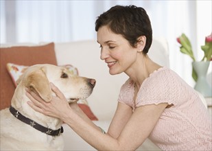 Woman petting dog in livingroom.