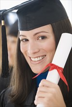 Woman wearing graduation cap and gown with diploma.