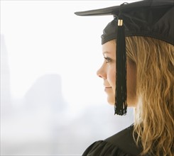 Woman wearing graduation cap and gown.