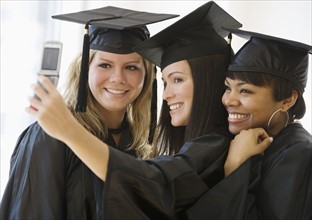 Multi-ethnic female graduates taking own photograph.