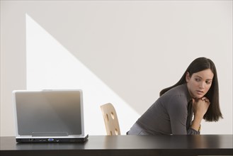 Woman looking over shoulder at laptop.