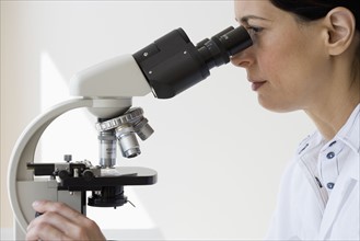 Female scientist looking into microscope.