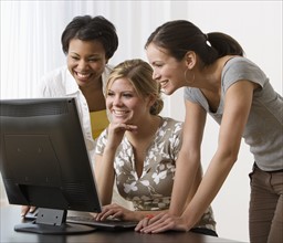 Multi-ethnic women looking at computer.