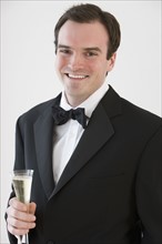 Portrait of groom holding champagne.