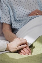 Nurse holding senior woman’s hand in hospital.