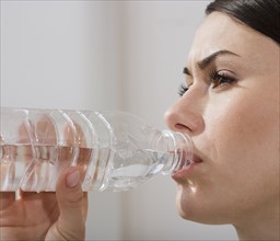 Close up of woman drinking from water bottle.