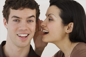 Woman whispering in boyfriend's ear.