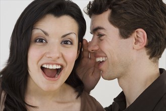 Man whispering in girlfriend's ear.