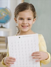 Portrait of girl holding paper in school.