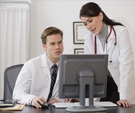 Doctors looking at computer in office.