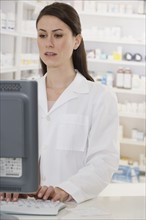 Female pharmacist typing on computer.
