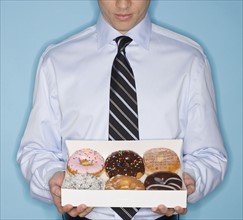 Businessman holding box of donut.