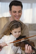 Father helping daughter play violin.