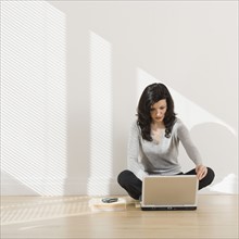 Woman looking at laptop on floor.