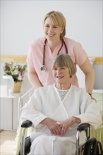 Nurse pushing senior woman in wheelchair.