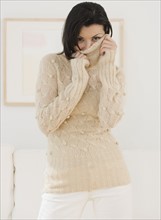 Woman pulling sweater over face.