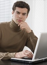 Portrait of businessman next to laptop.
