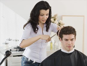 Female hair stylist cutting man’s hair.