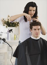 Female hair stylist cutting man’s hair.