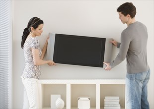 Couple hanging television on wall.