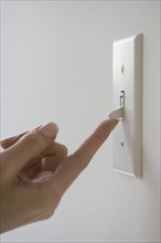 Close up of woman turning on light switch.