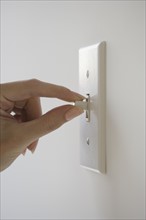 Close up of woman turning light switch.