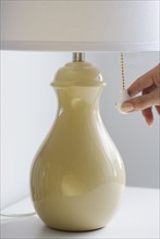 Close up of woman pulling chain on lamp.