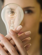 Woman holding light bulb in front of face.