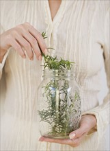 Woman taking herbs out of jar.
