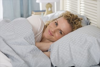 Portrait of woman laying in bed.