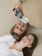 Couple video recording themselves on floor.
