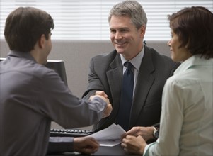 Businessman shaking hands with couple.